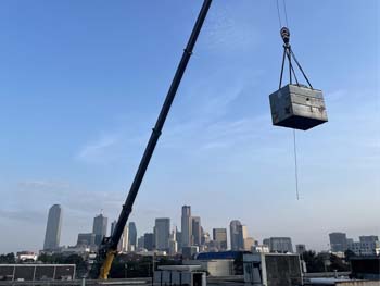 Crane lifting HVAC equipment at a job site 