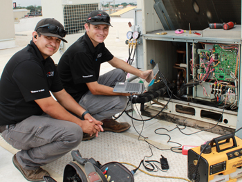 Two Dallas Mechanical technicians smiling while providing maintenance on a unit