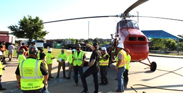 Dallas Mechanical employees wearing safety vests with a red helicopter in the background